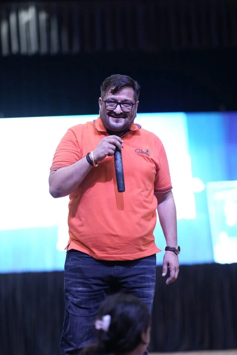 Mukesh Sinduria speaking on stage with microphone